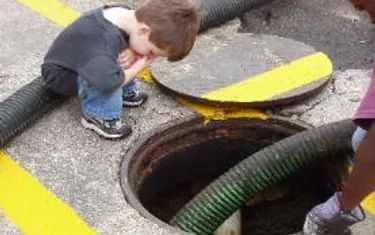 Owner Cameron Bates as a child looking into a grease trap