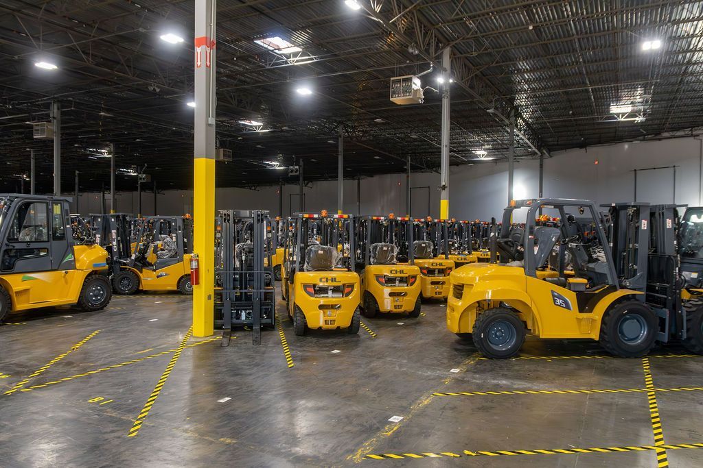 Yellow forklifts parked in a warehouse aisle under bright overhead lights.