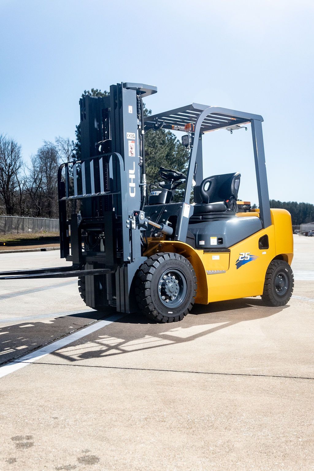 Yellow forklift parked on a concrete lot under a clear sky