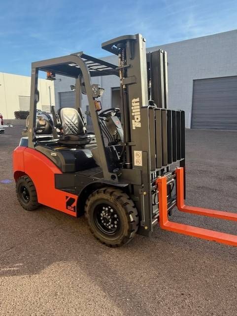 Orange-and-black forklift parked outdoors beside a warehouse building
