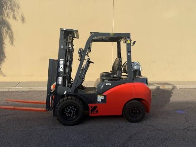 Red forklift parked side-on against a beige wall on a paved surface.