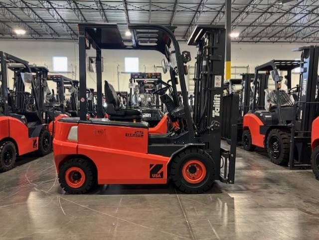 Orange forklift in a warehouse showroom, with several forklifts lined up behind it.