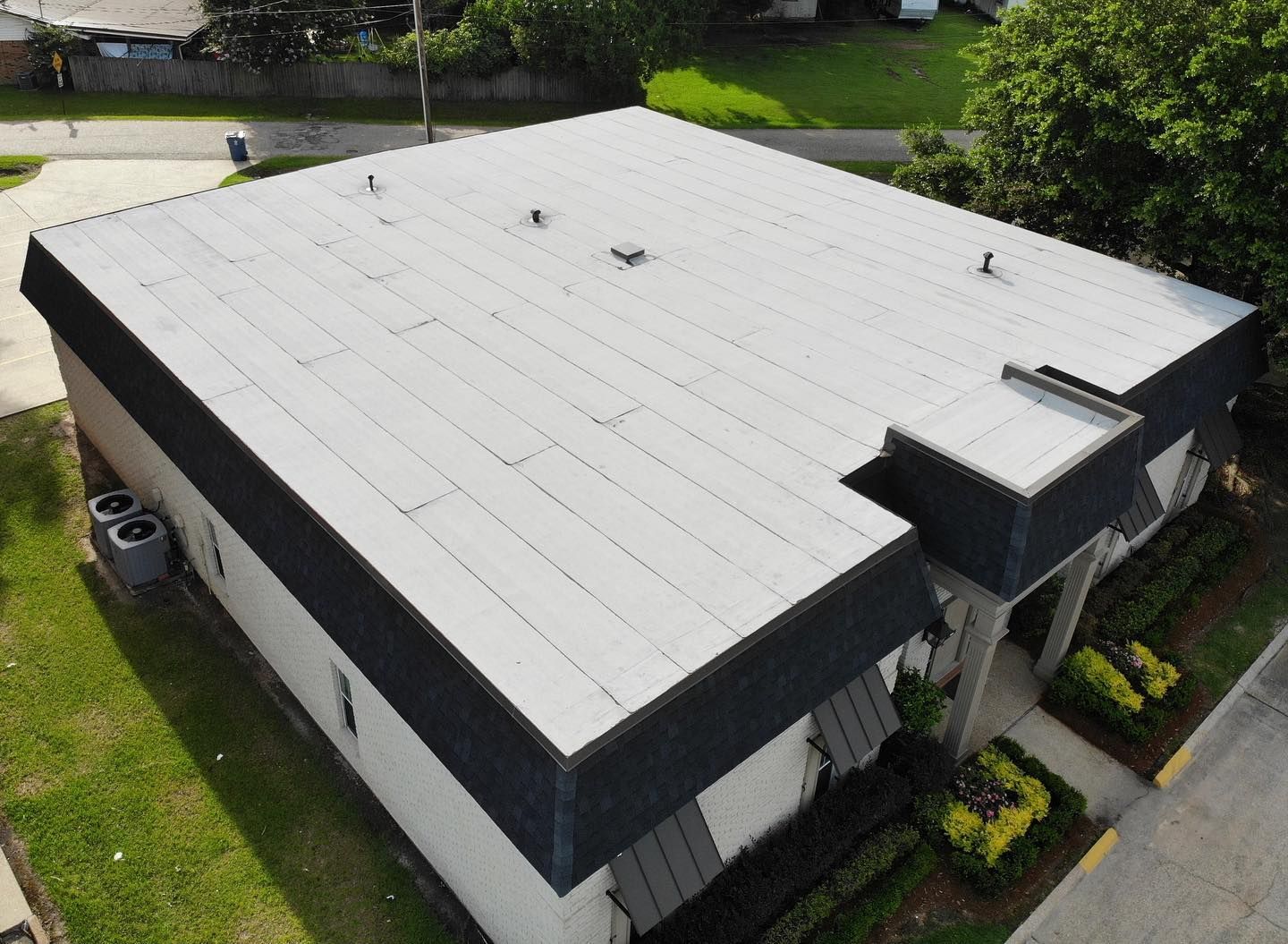 Aerial view of a building with a flat, light-colored roof and black trim.