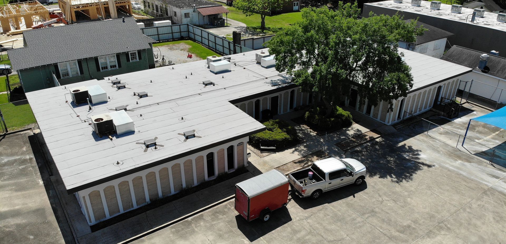 Aerial view of a commercial building with a red trailer and white truck parked outside.