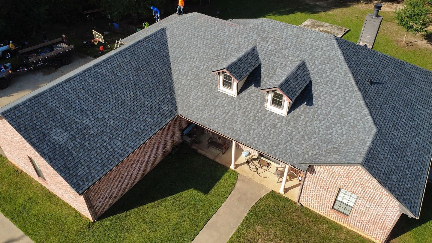 Overhead view of a brick house with a gray shingled roof and two dormers.