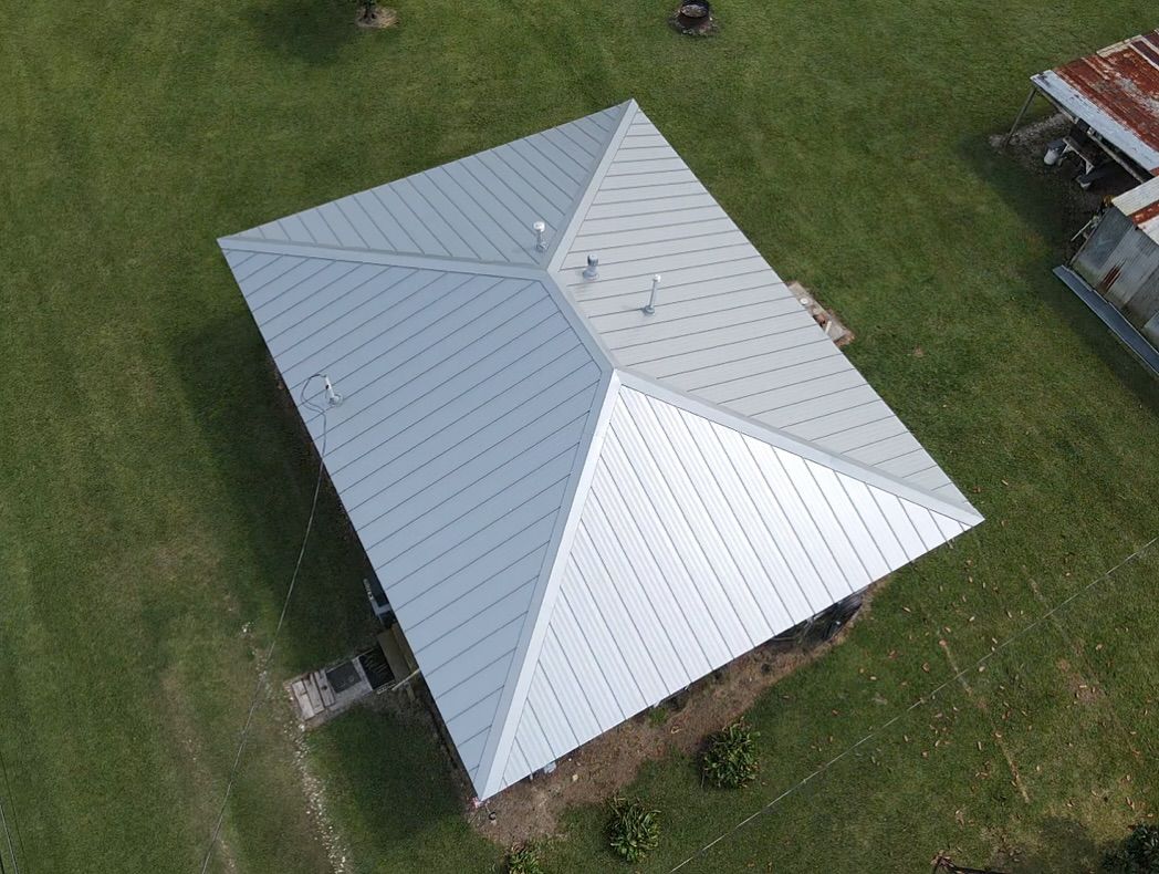 Overhead view of a building with a silver metal roof, set in a grassy field.