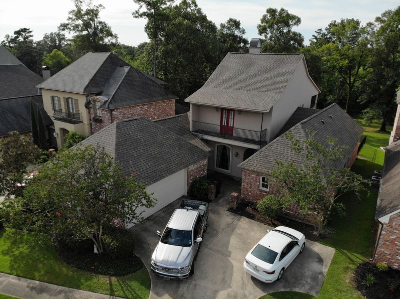 Aerial view of a two-story house with a pickup truck and sedan parked in the driveway.