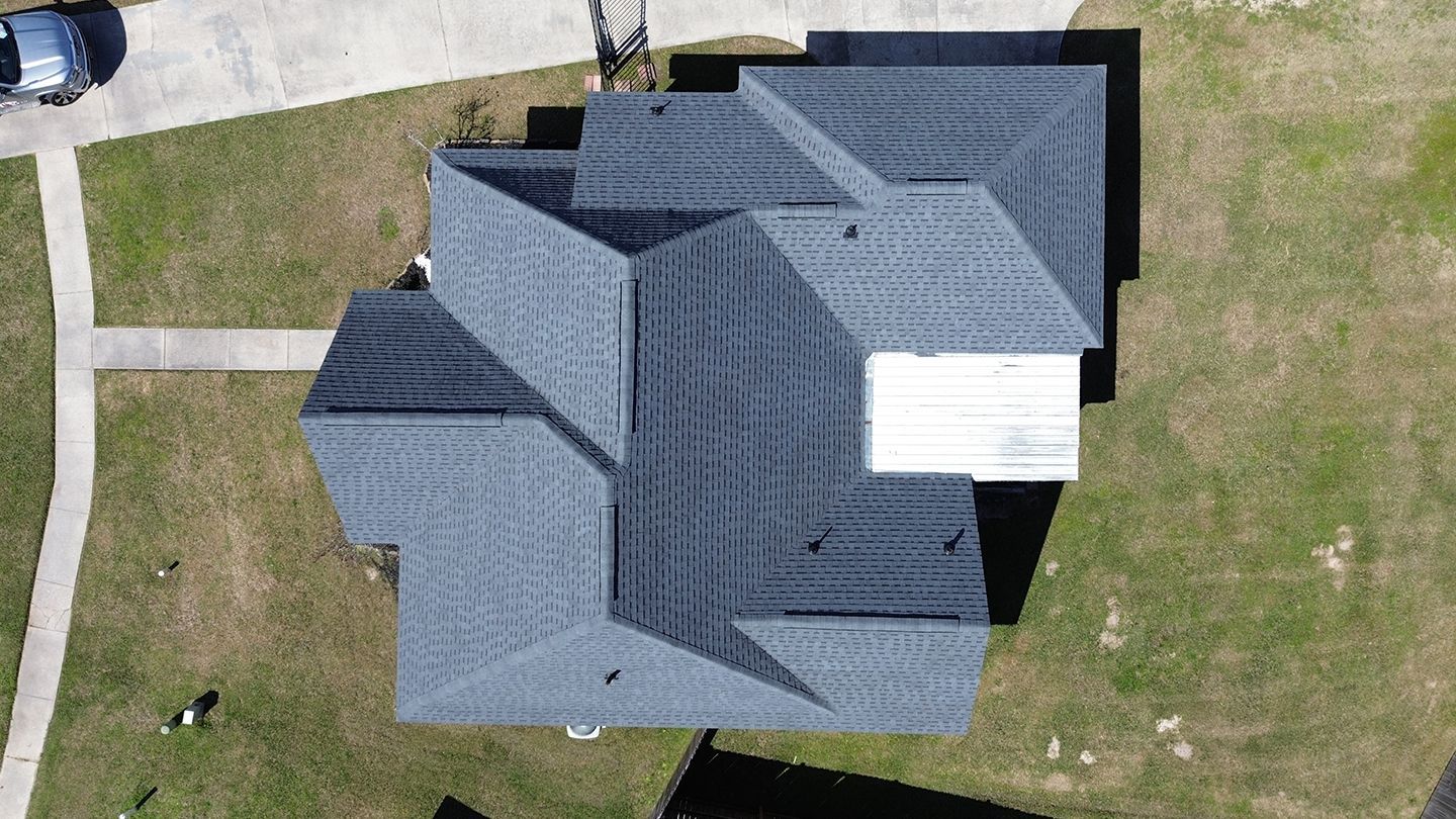 Overhead view of a house with a dark gray shingle roof and green lawn.