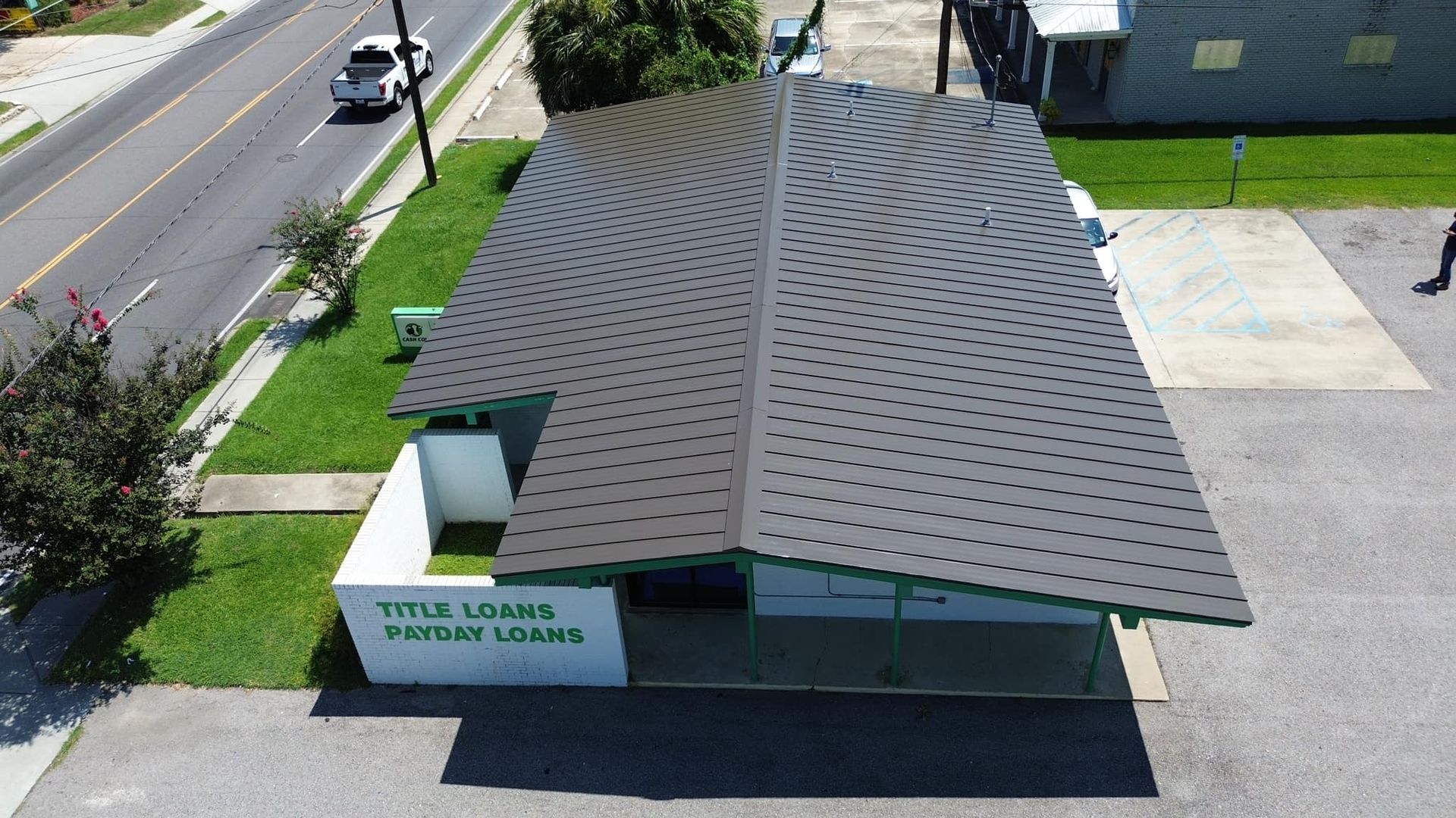Title Loans and Payday Loans building with a unique gray, leaf-shaped roof. Green trim and a lawn.