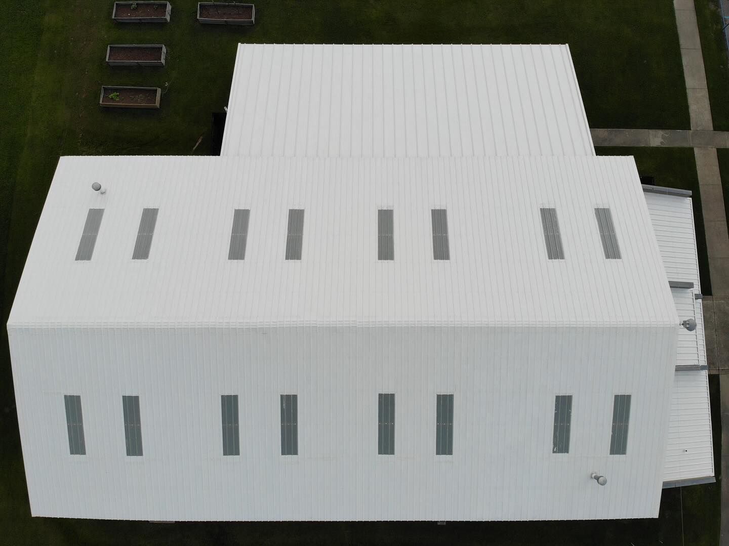 Overhead view of a white building with multiple rectangular vents on a green lawn.