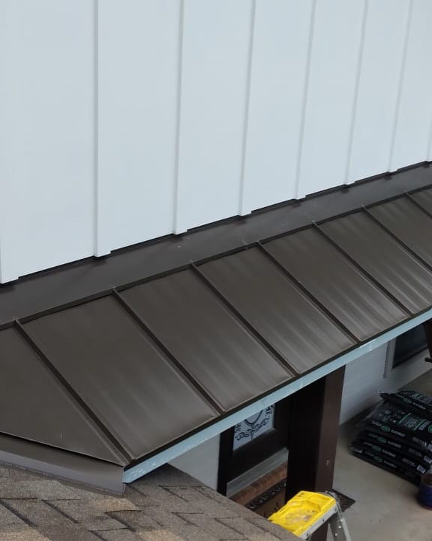 Brown metal roof and white siding on a building, shot from above.