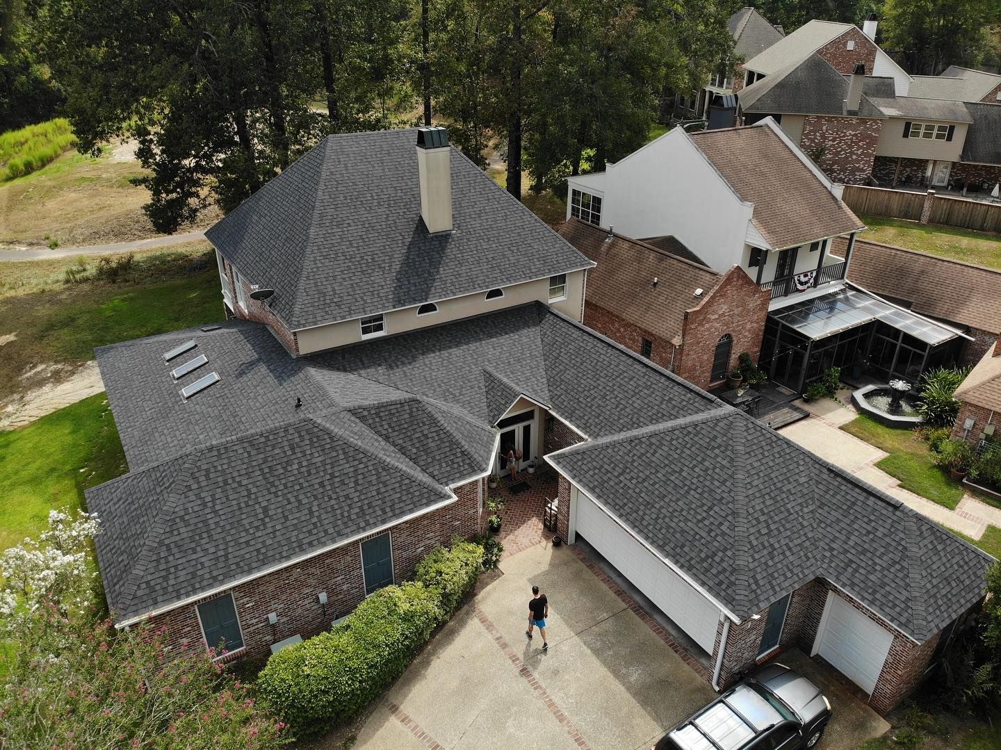 Aerial view of a house with a dark gray roof and a car parked in the driveway.