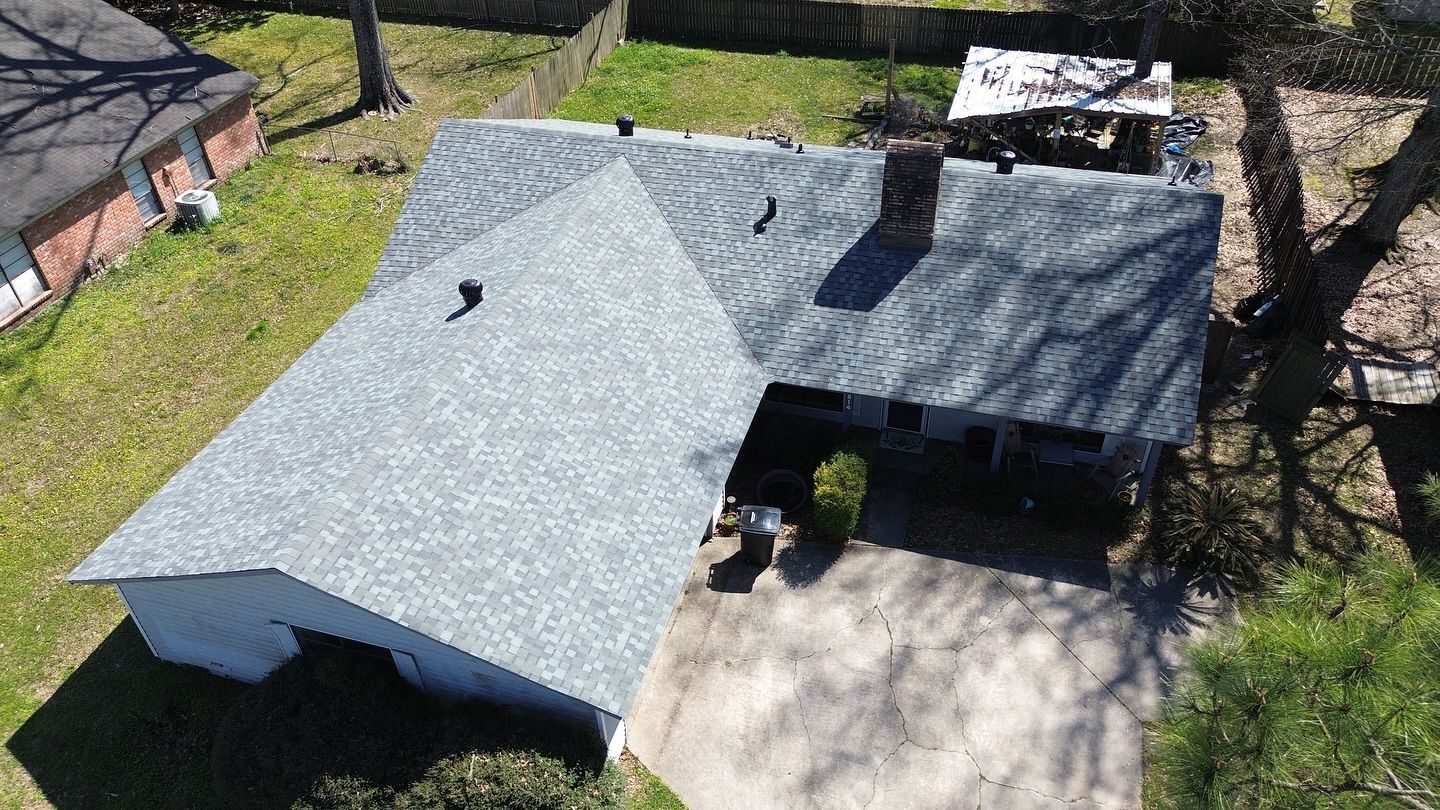Overhead view of a house with a gray shingle roof, a chimney, and a small yard.