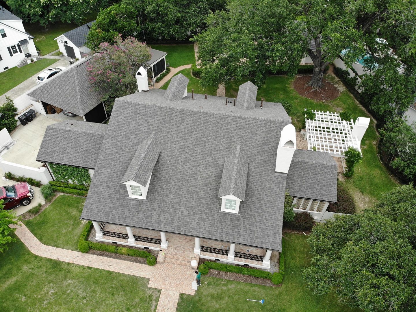 Aerial view of a house with a gray roof, green lawn, and brick pathway.