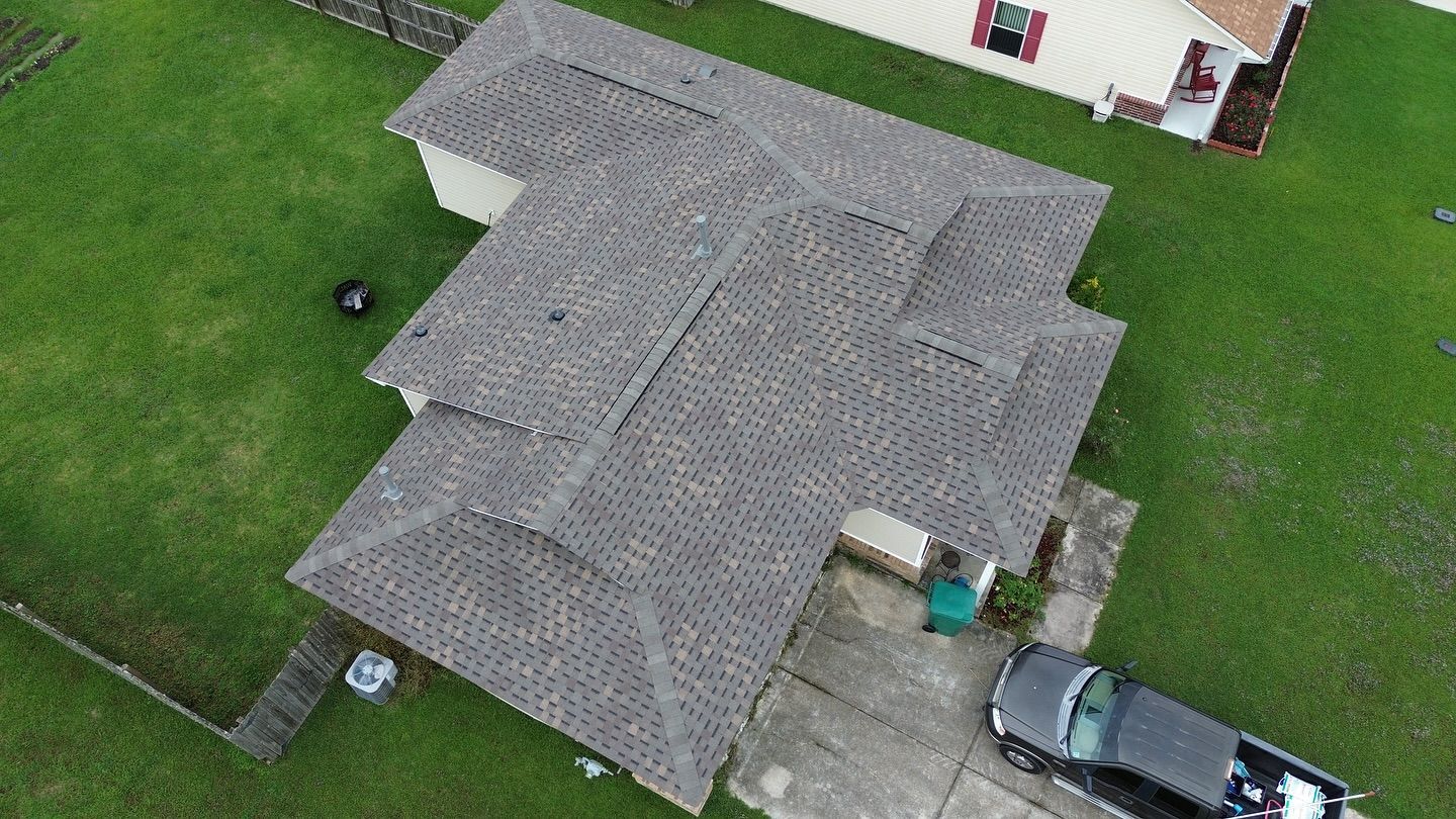 Overhead view of a house with a gray roof and a gray pickup truck parked in the driveway on a green lawn.
