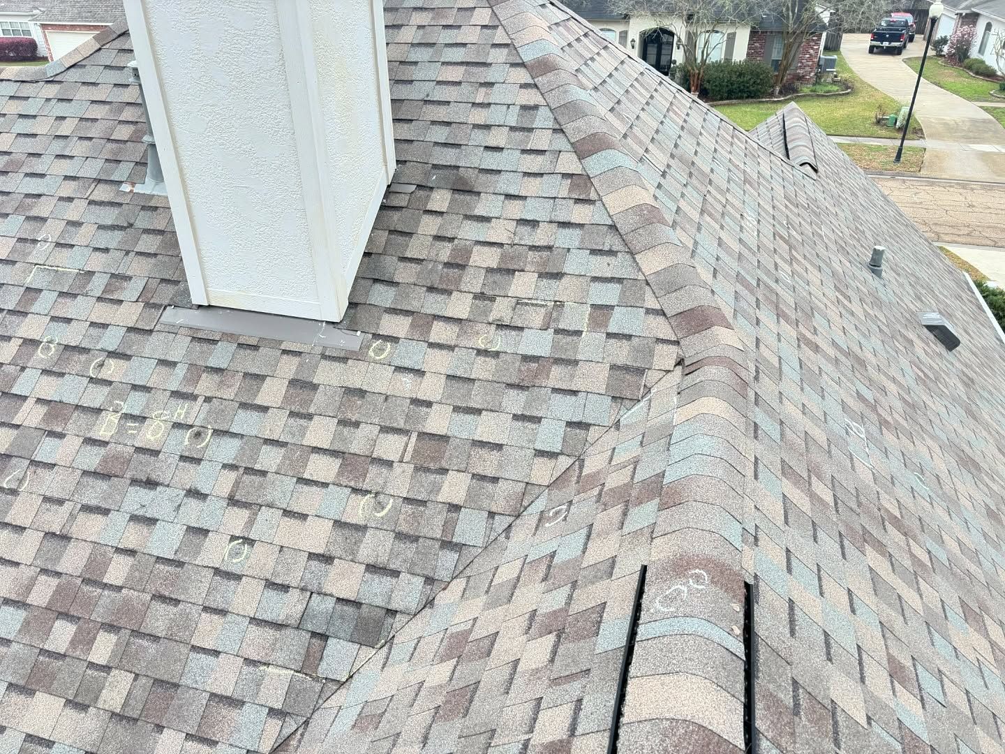 Brown shingled roof with a chimney, angled view. Sunlight illuminates the details.