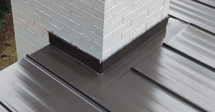 Chimney with black flashing on a corrugated metal roof.