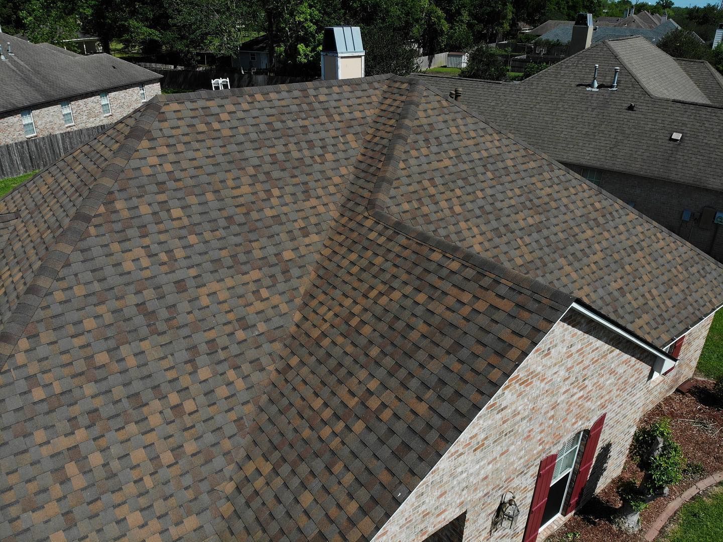 Brown asphalt shingle roof on a residential house, aerial view.