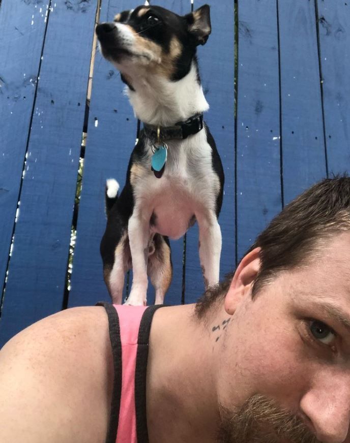 A man laying down with a dog standing on his head