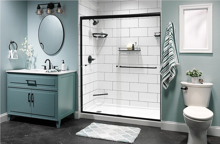 Modern bathroom with teal vanity, round mirror, glass shower, toilet, and striped towels
