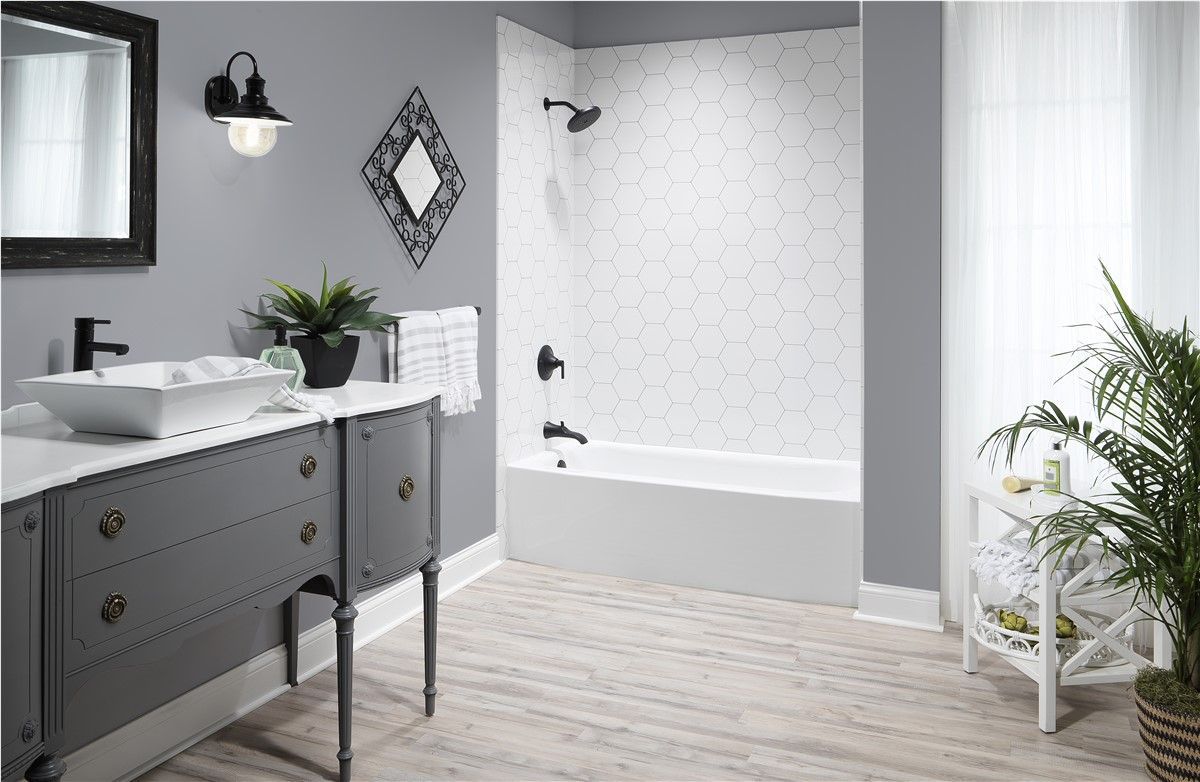 Modern bathroom with gray vanity, white tub-shower, and light wood floor accents