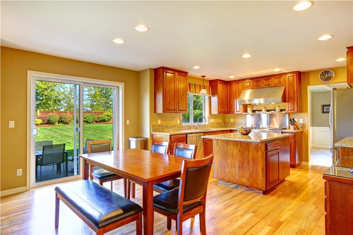 Bright open kitchen and dining area with wood cabinets, island, and sliding glass doors to a patio
