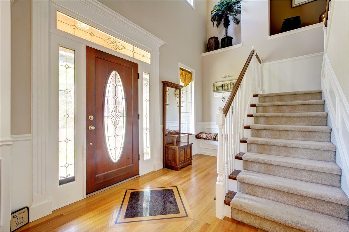 Bright foyer with front door, staircase, and hardwood floor