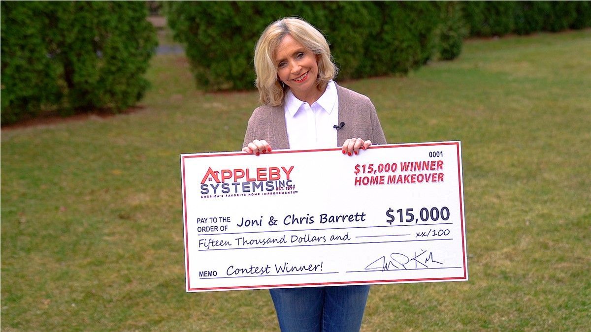 Woman holding oversized $15,000 check outdoors on a lawn.