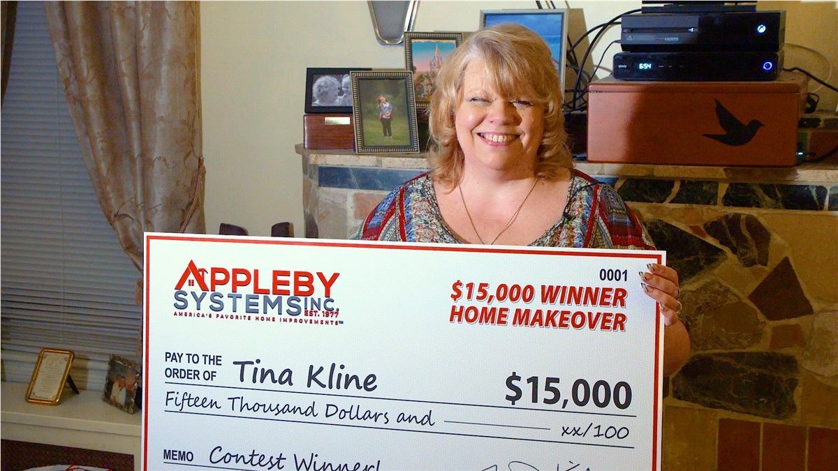 Woman smiling beside a $15,000 Appleby Systems home makeover check in a living room
