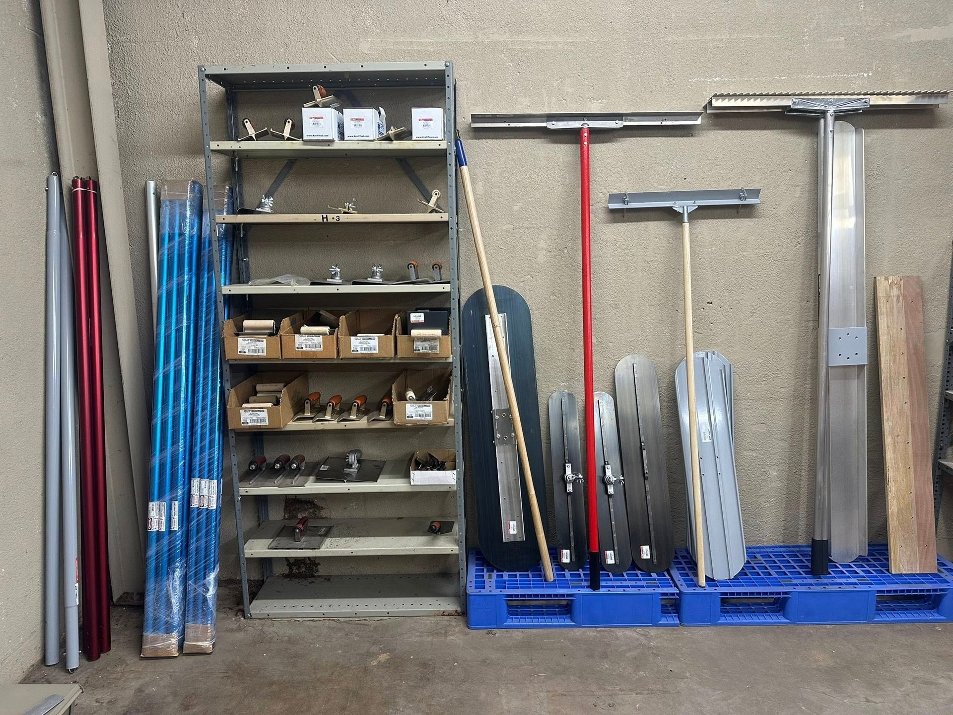 Shelving unit and tools in a workshop. Contains poles, hardware, screeds, and floats.