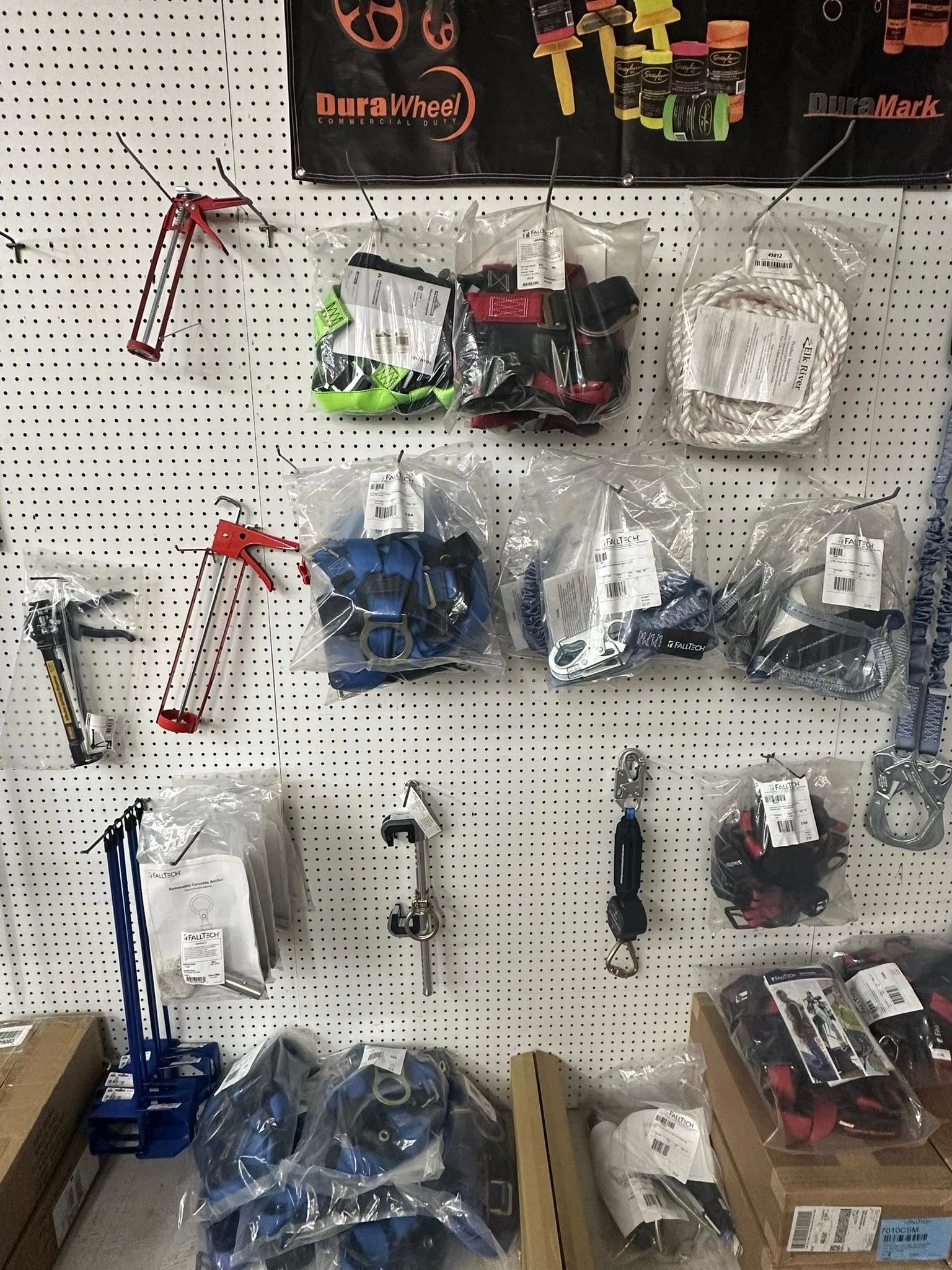 Wall display of bagged archery equipment, including sights and stabilizers, on a pegboard.