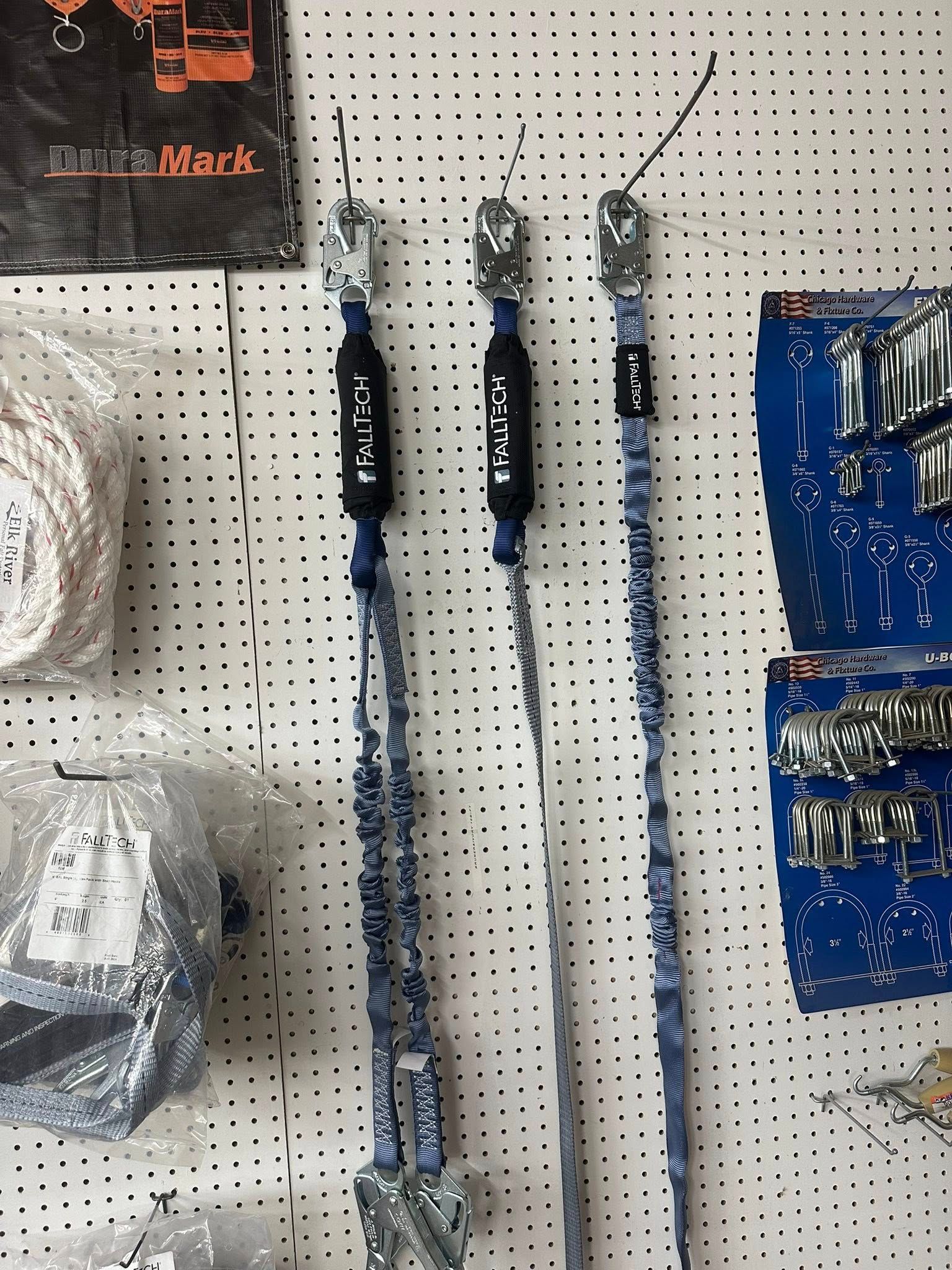 Three blue safety lanyards hanging on a pegboard, displayed in a store.