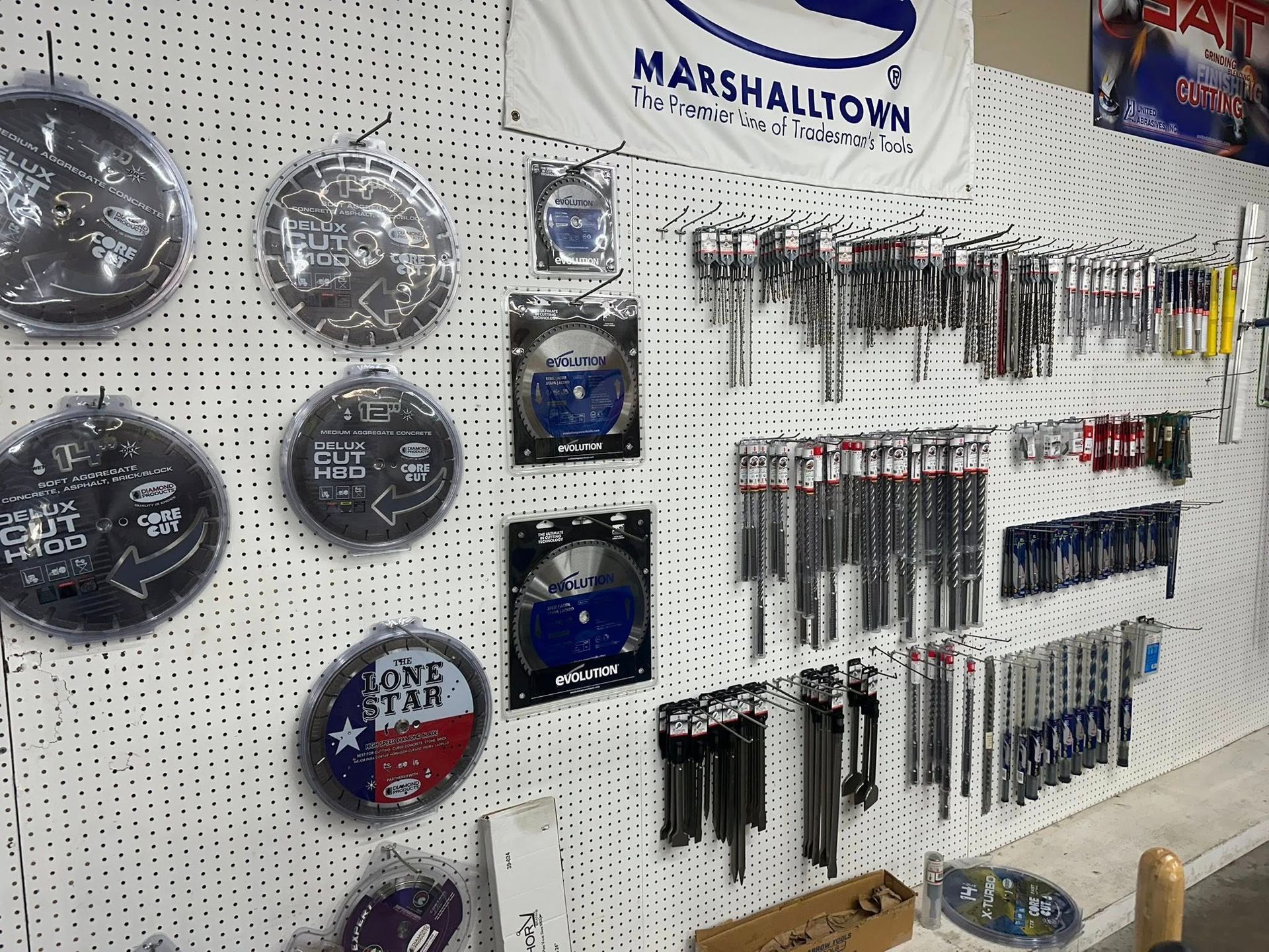 Tools and trowels displayed on a pegboard, with a Marshalltown banner overhead.