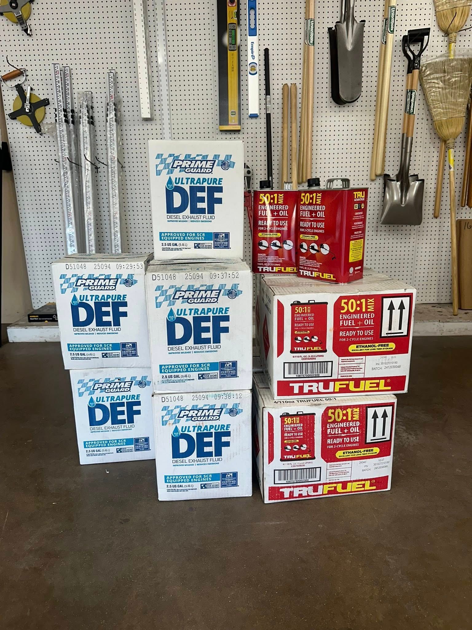 Stacked containers of DEF fluid and motor oil against a backdrop of tools.