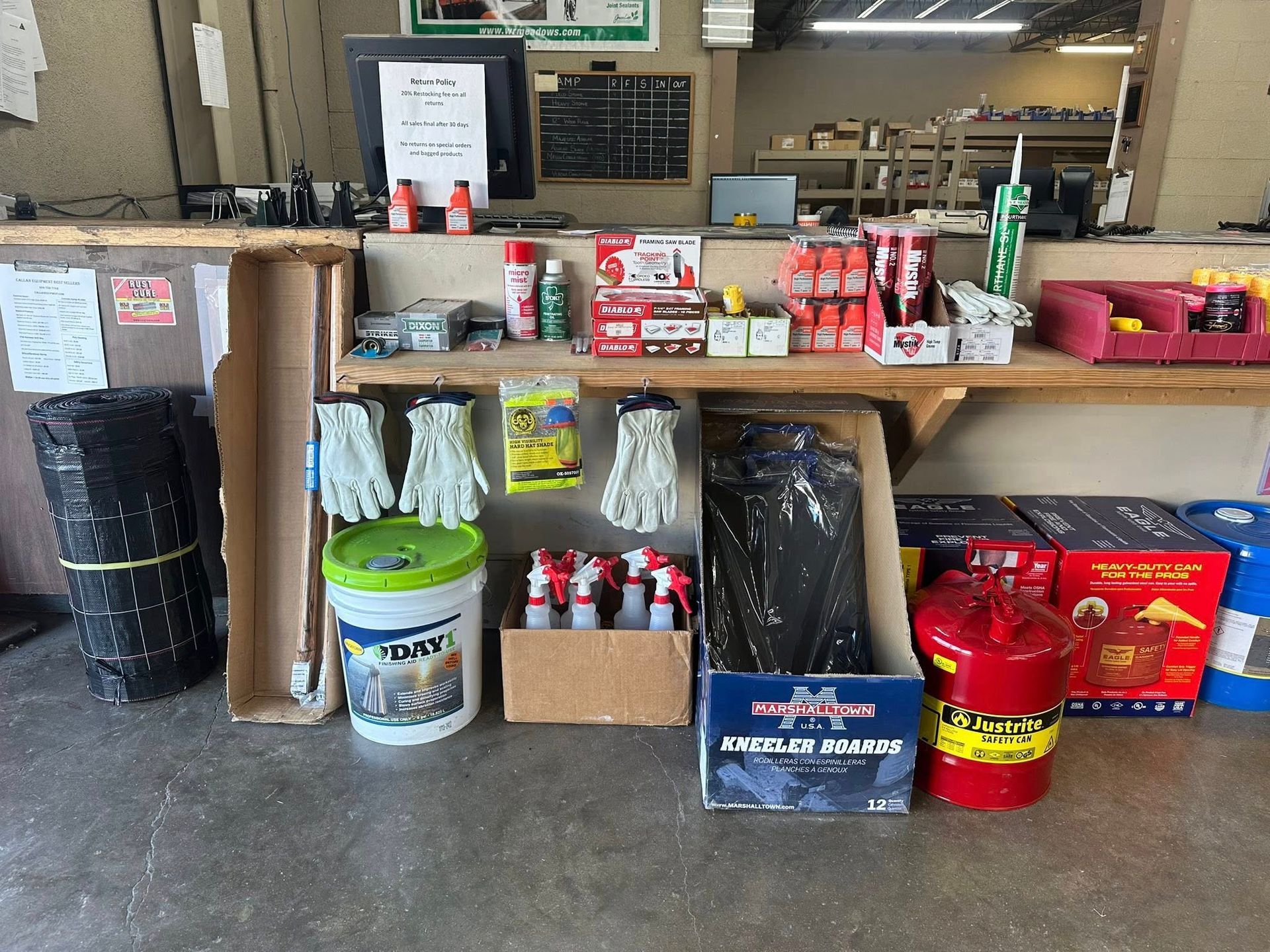Interior of a hardware store counter with various items for sale, including gloves, paint, and fuel cans.