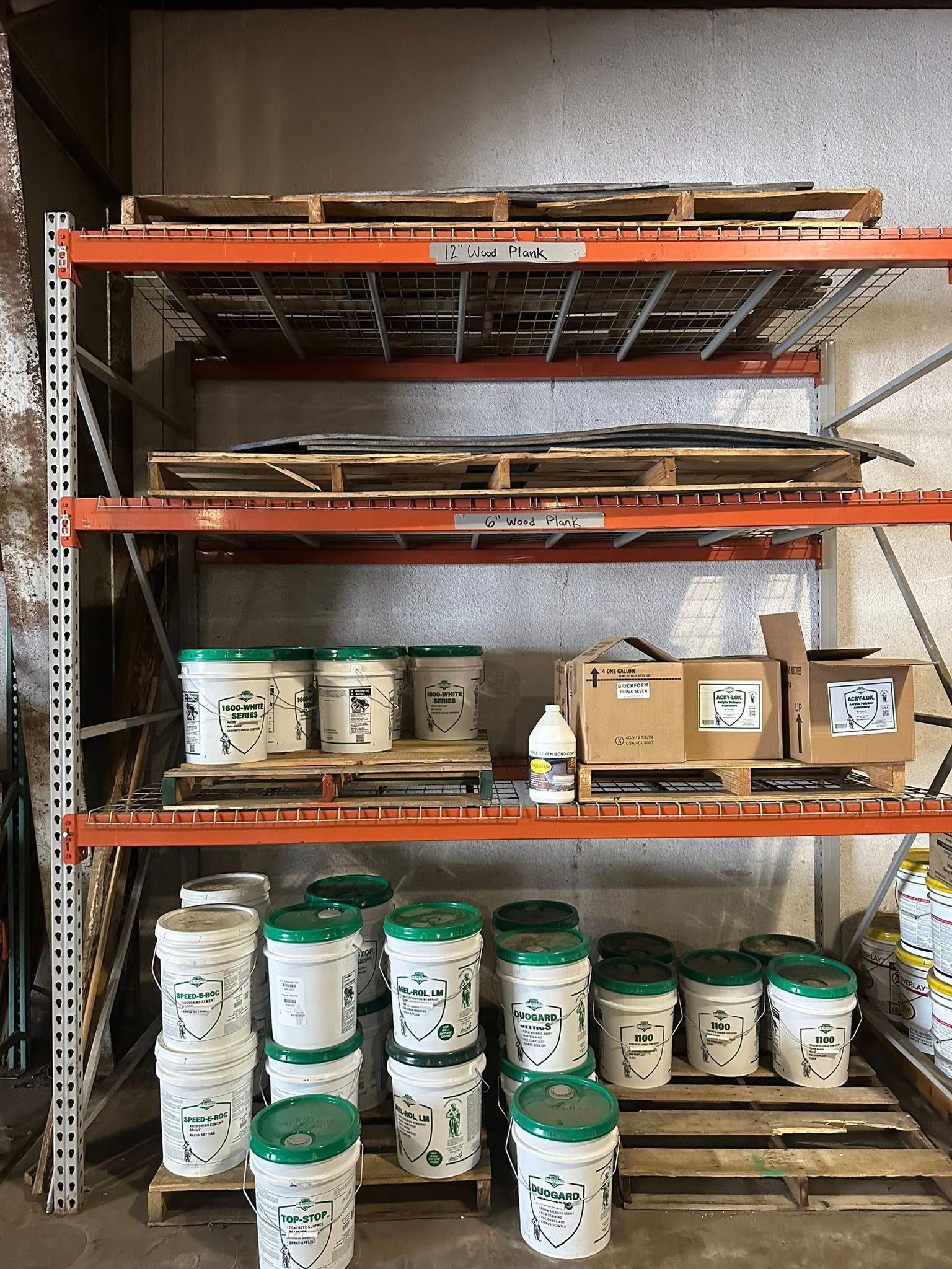 Shelving unit with pallets and buckets of paint.