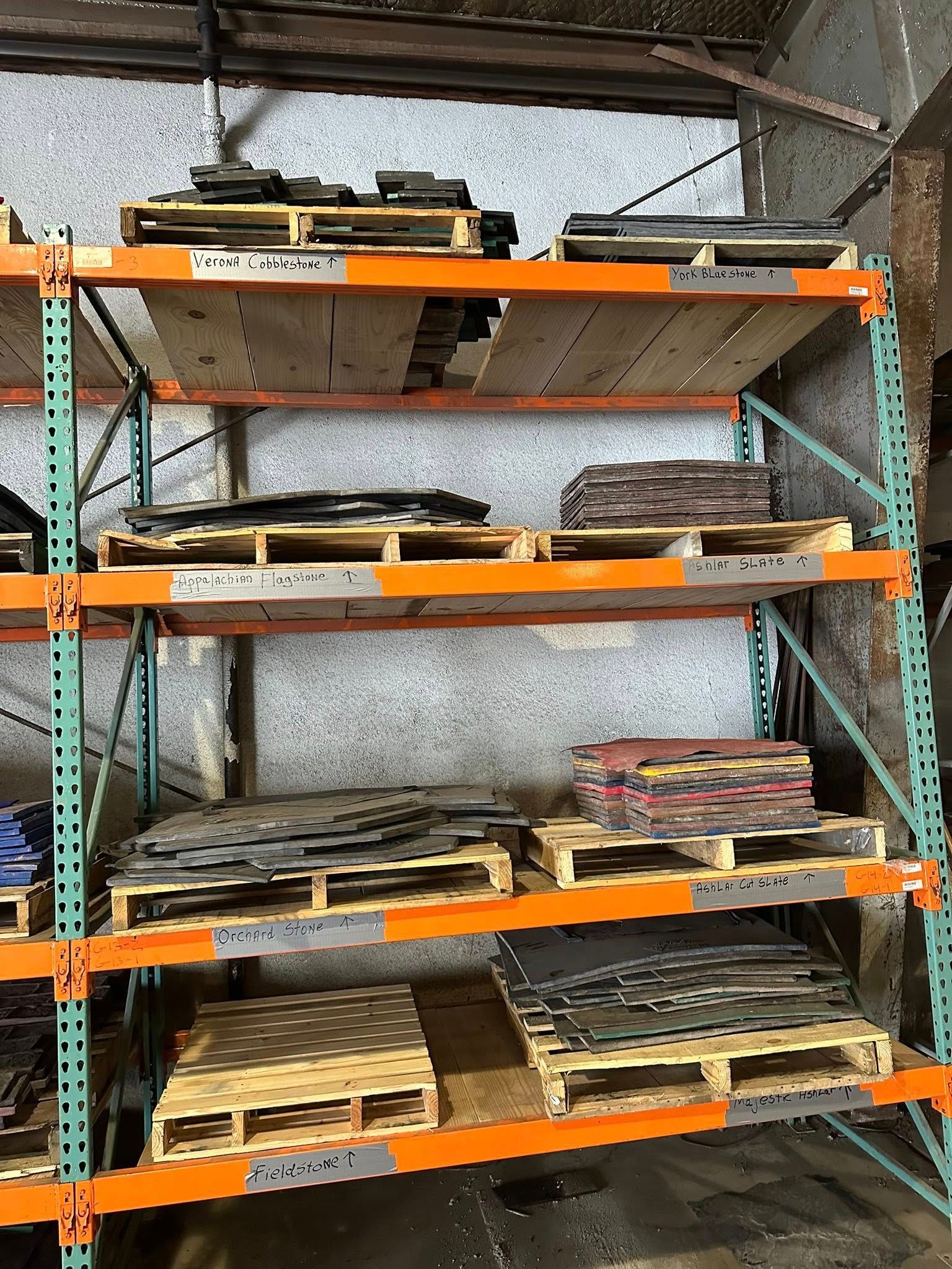 Shelving unit with wooden pallets holding various dark-colored materials in an industrial setting.
