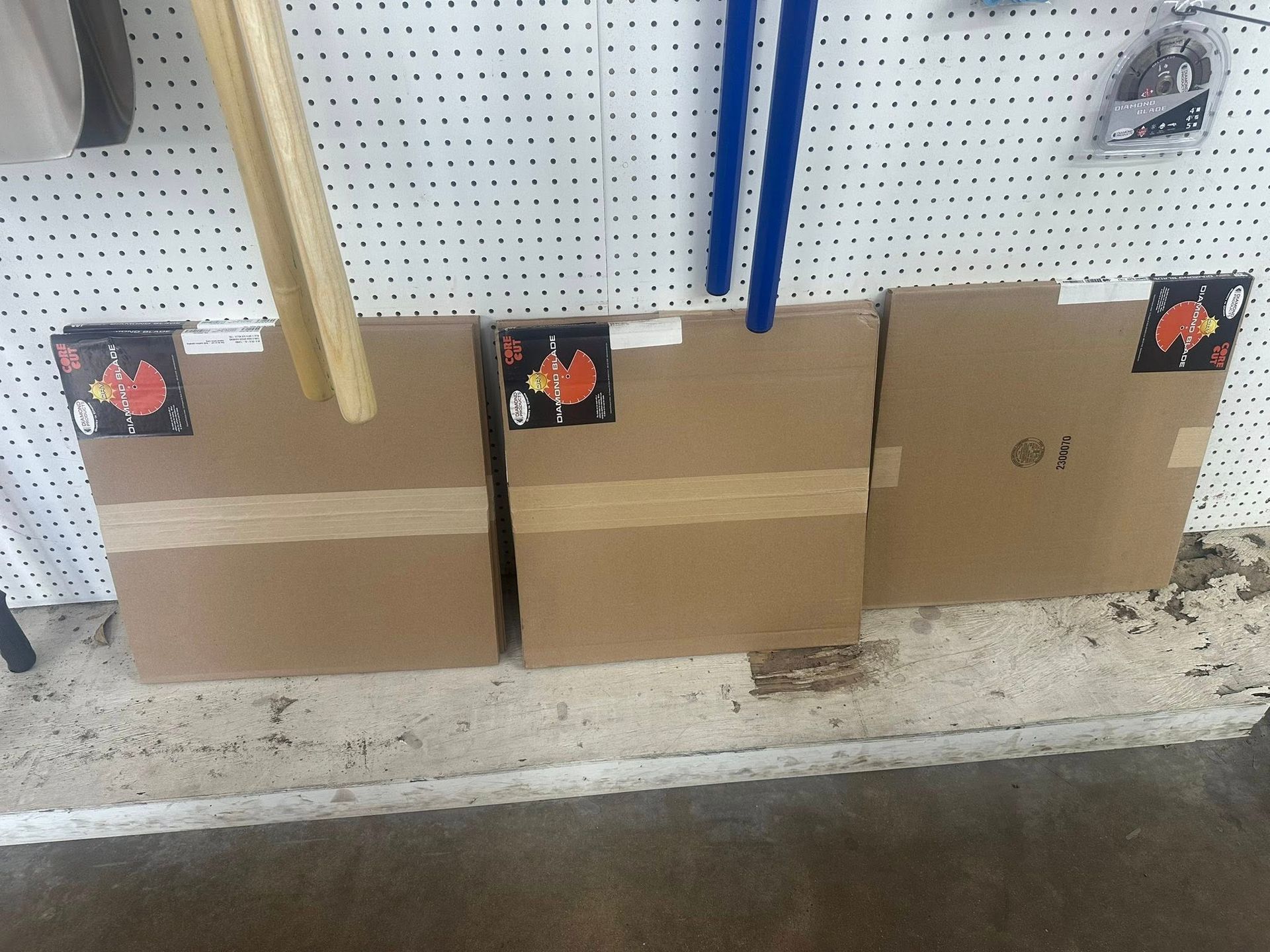 Three taped cardboard boxes against a pegboard wall.
