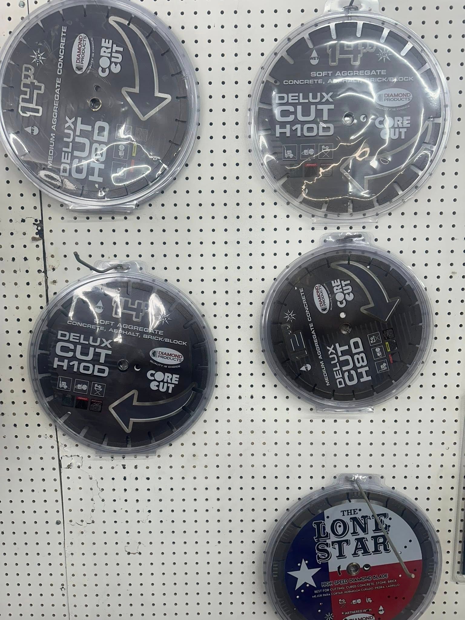 Circular saw blades hanging on a pegboard, featuring text and arrows, with one Texas flag design.