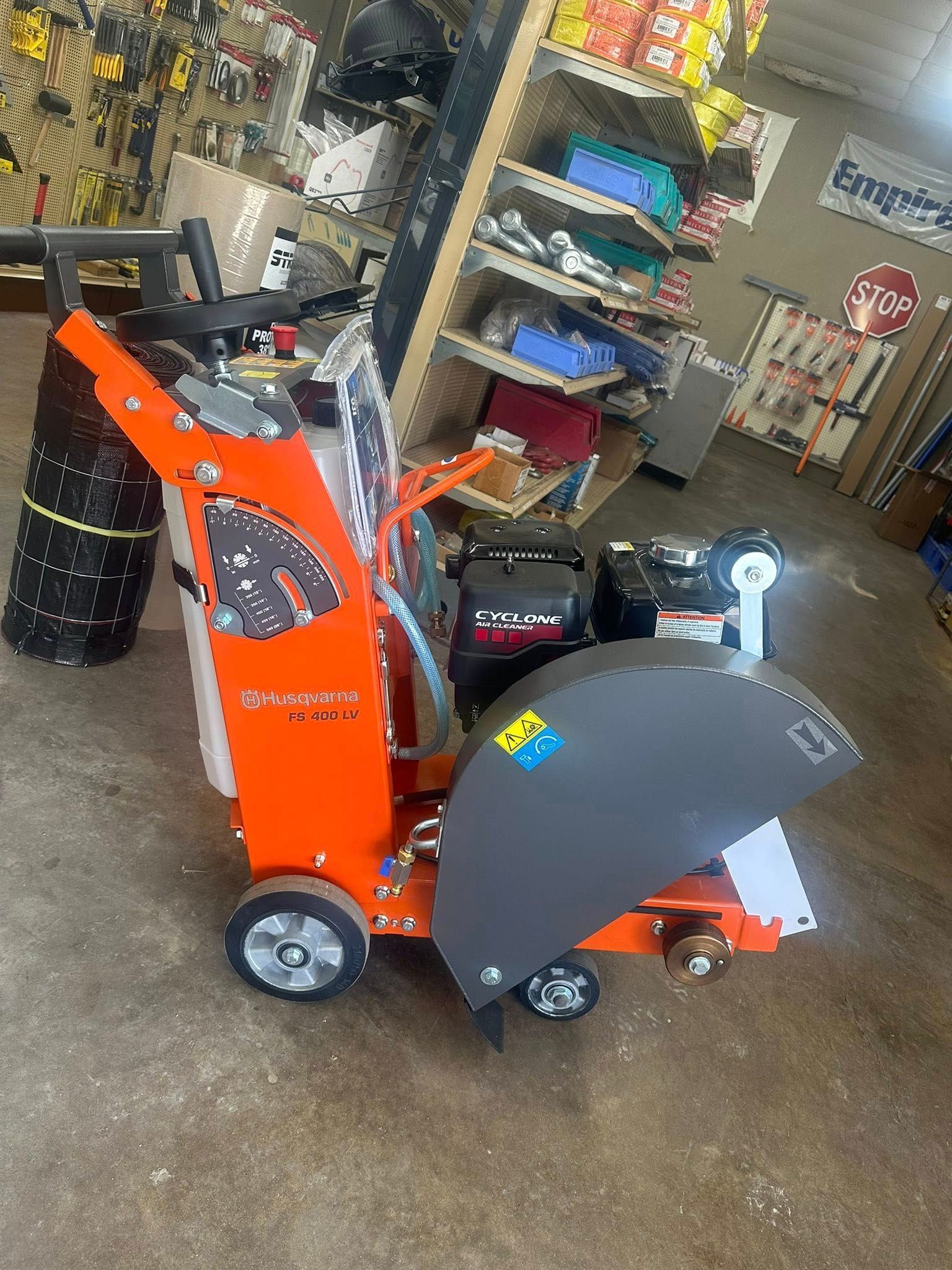 Orange concrete saw with a black blade guard on a concrete floor.