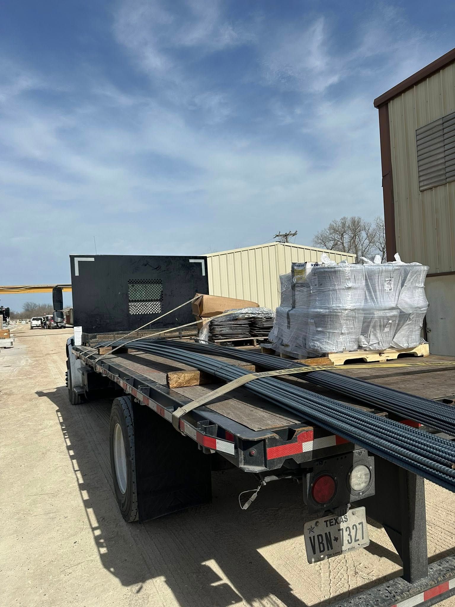 Flatbed truck loaded with rebar and construction materials.