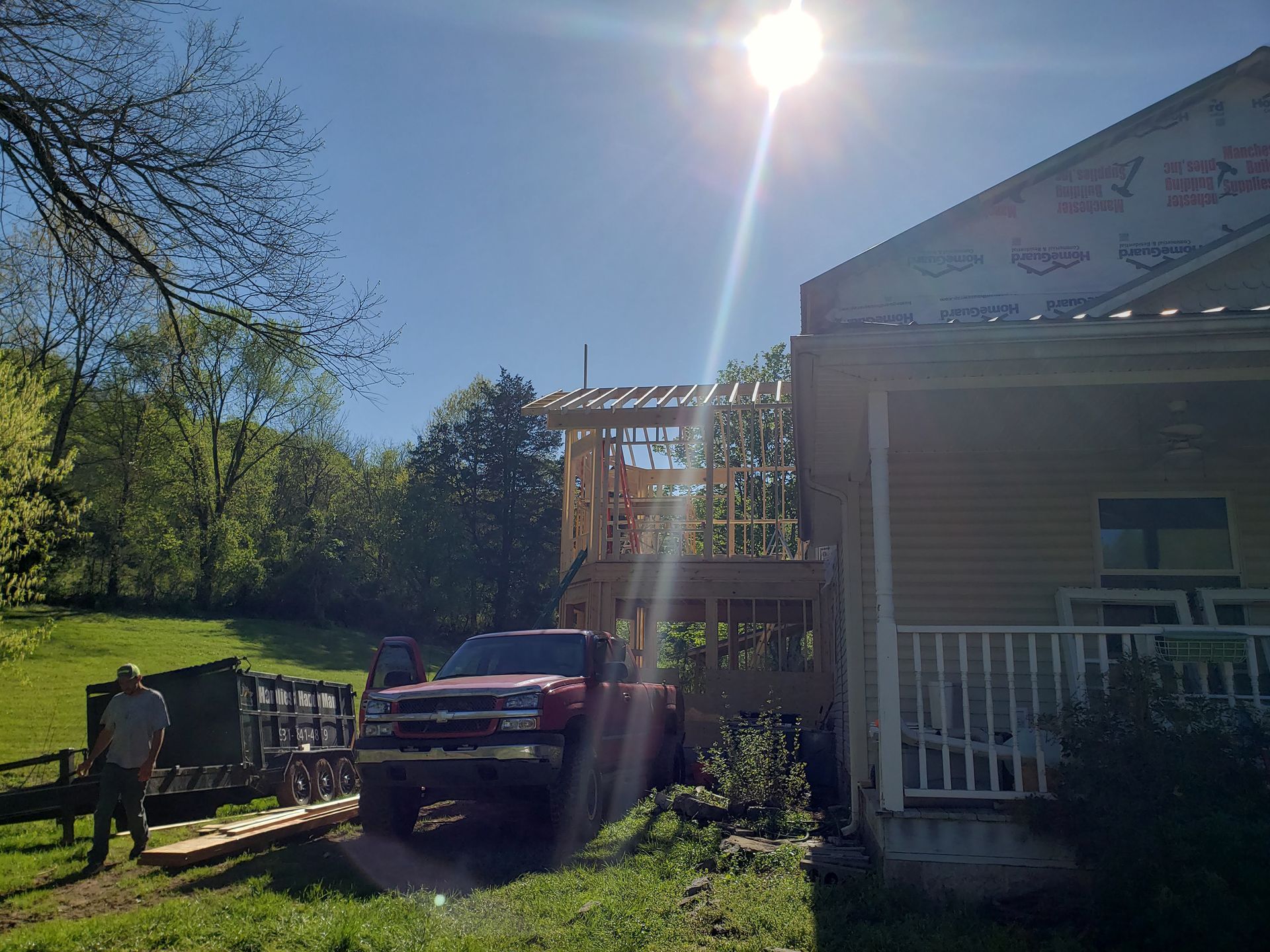 Construction site with a red truck, framing, and workers on a sunny day.