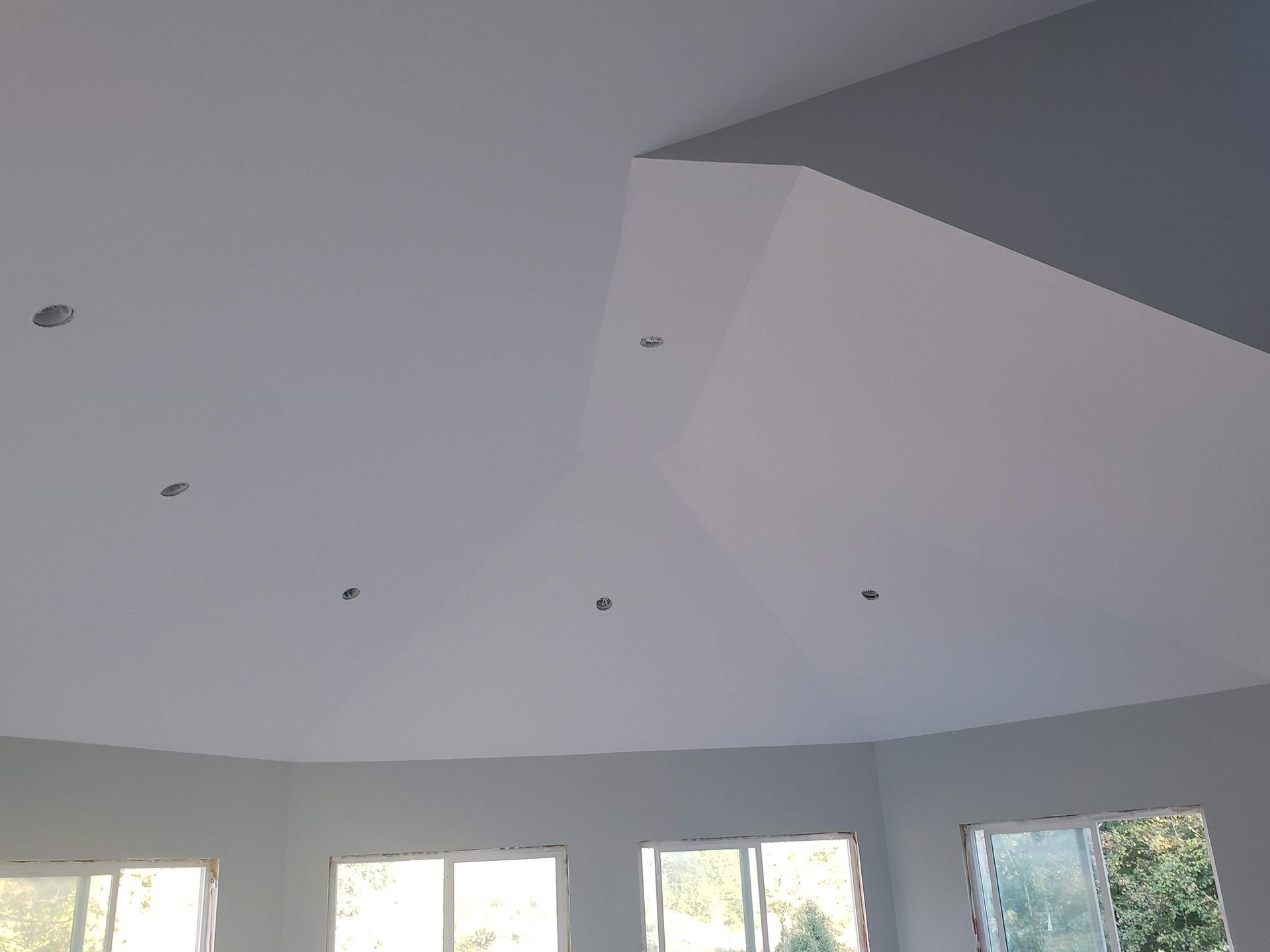 White interior ceiling with recessed lights, sloped sections, and light gray walls.
