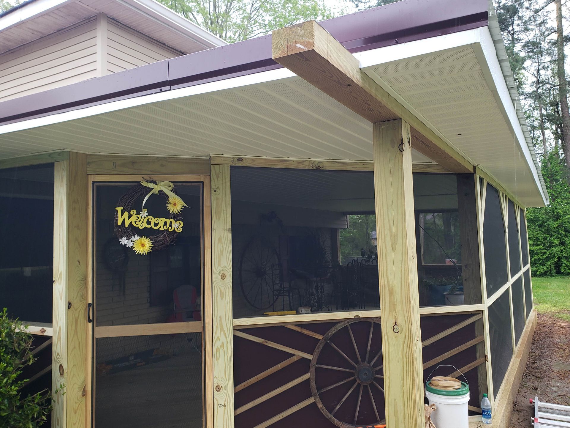 Screened porch with wood posts, brown siding, and a 