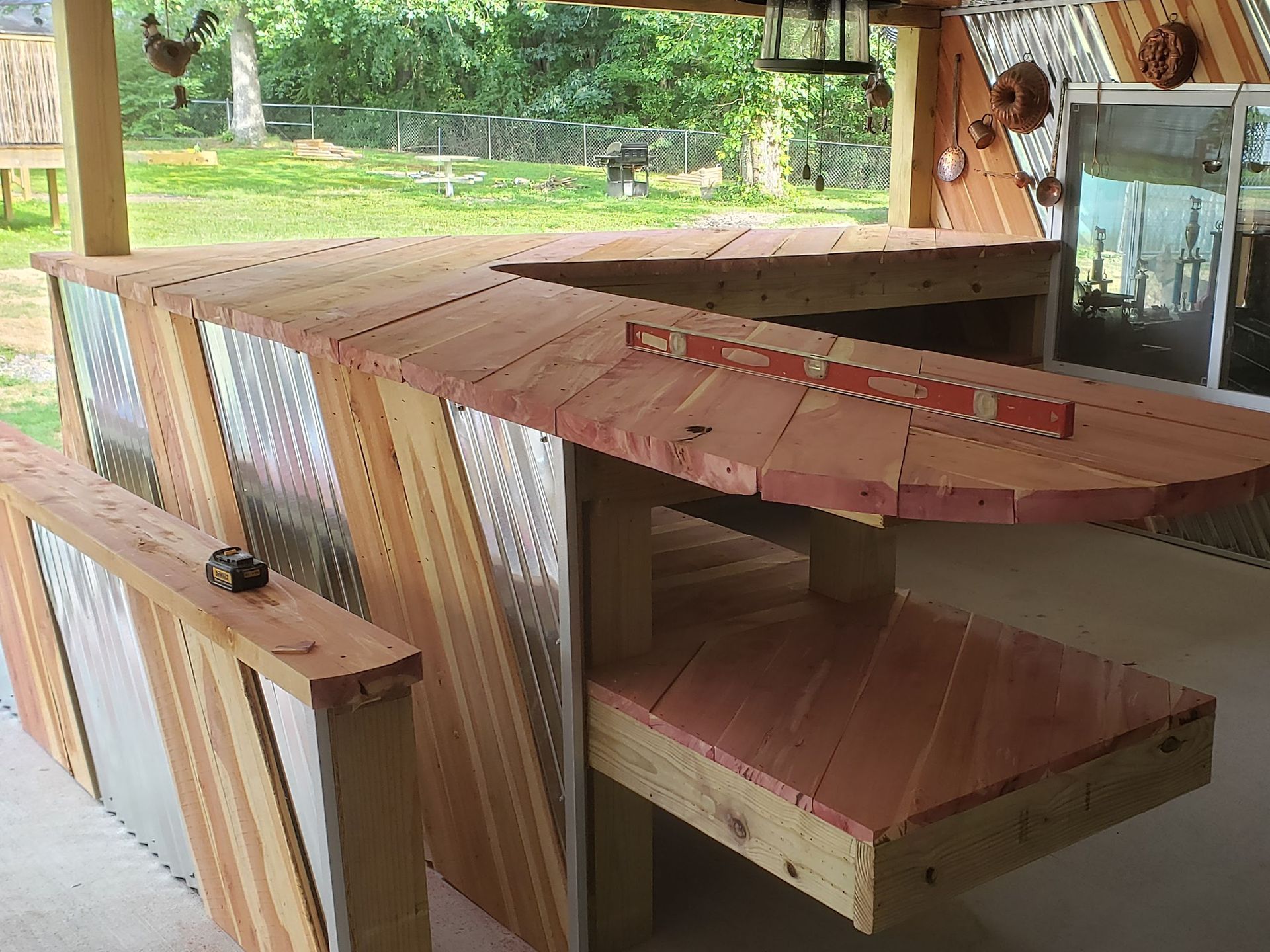 Outdoor wooden bar with corrugated metal siding and a level resting on the countertop.