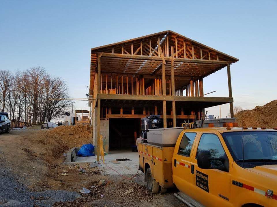 Construction of a two-story wooden building, with a yellow truck parked in front.