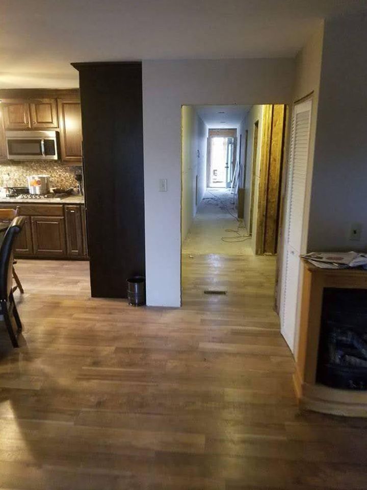 Kitchen and hallway view with dark cabinetry, wooden floors, and a dark structural beam.
