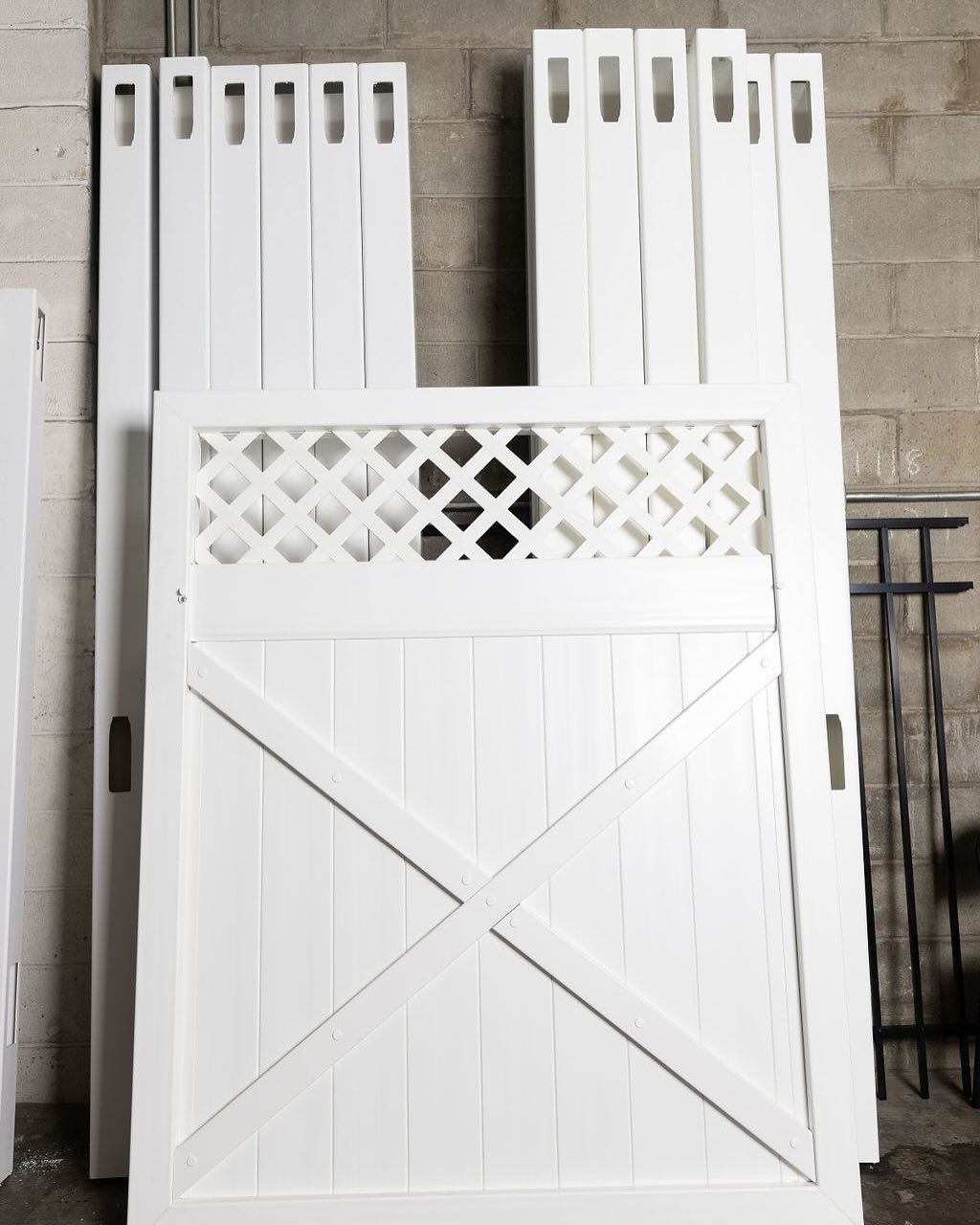 White wooden gate and fence parts against a gray brick wall.