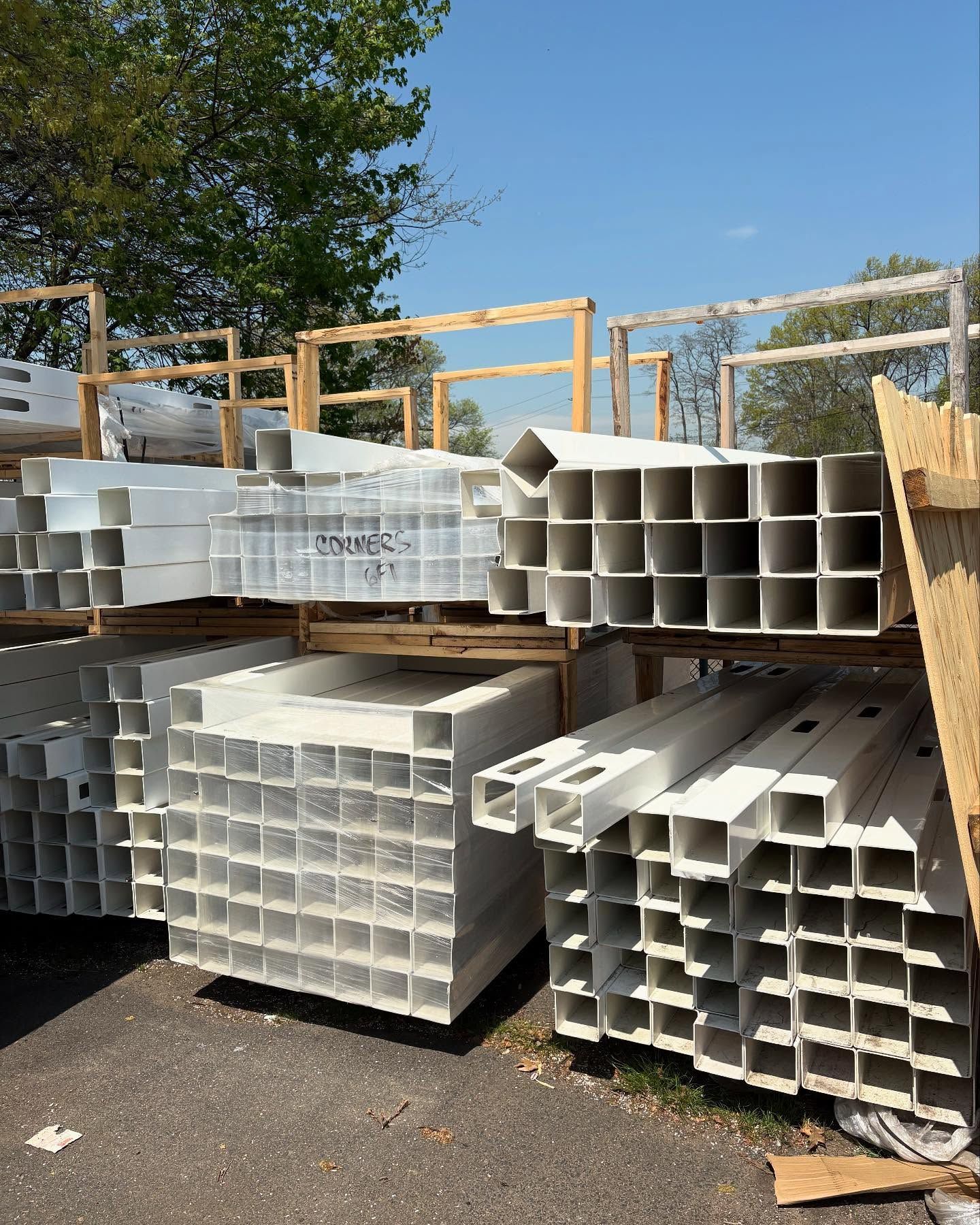 Stacks of white square posts in a lumberyard under a blue sky.