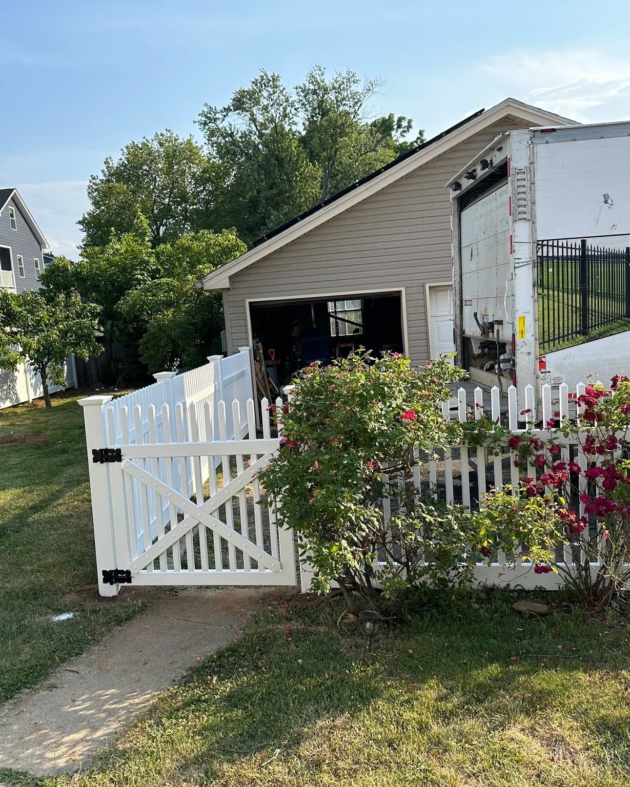 White picket fence with gate leading to a garage in a suburban setting.